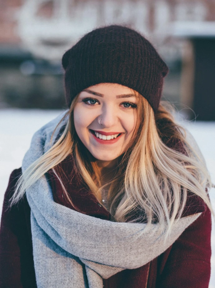 smiling woman wearing brown scarf and maroon coat on snow field